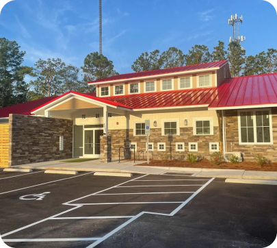 Pawville Midtown location: Building with a red roof and stone facade in a parking lot with handicap accessible parking.